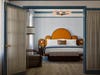 A bedroom with a scalloped headboard and light blue walls