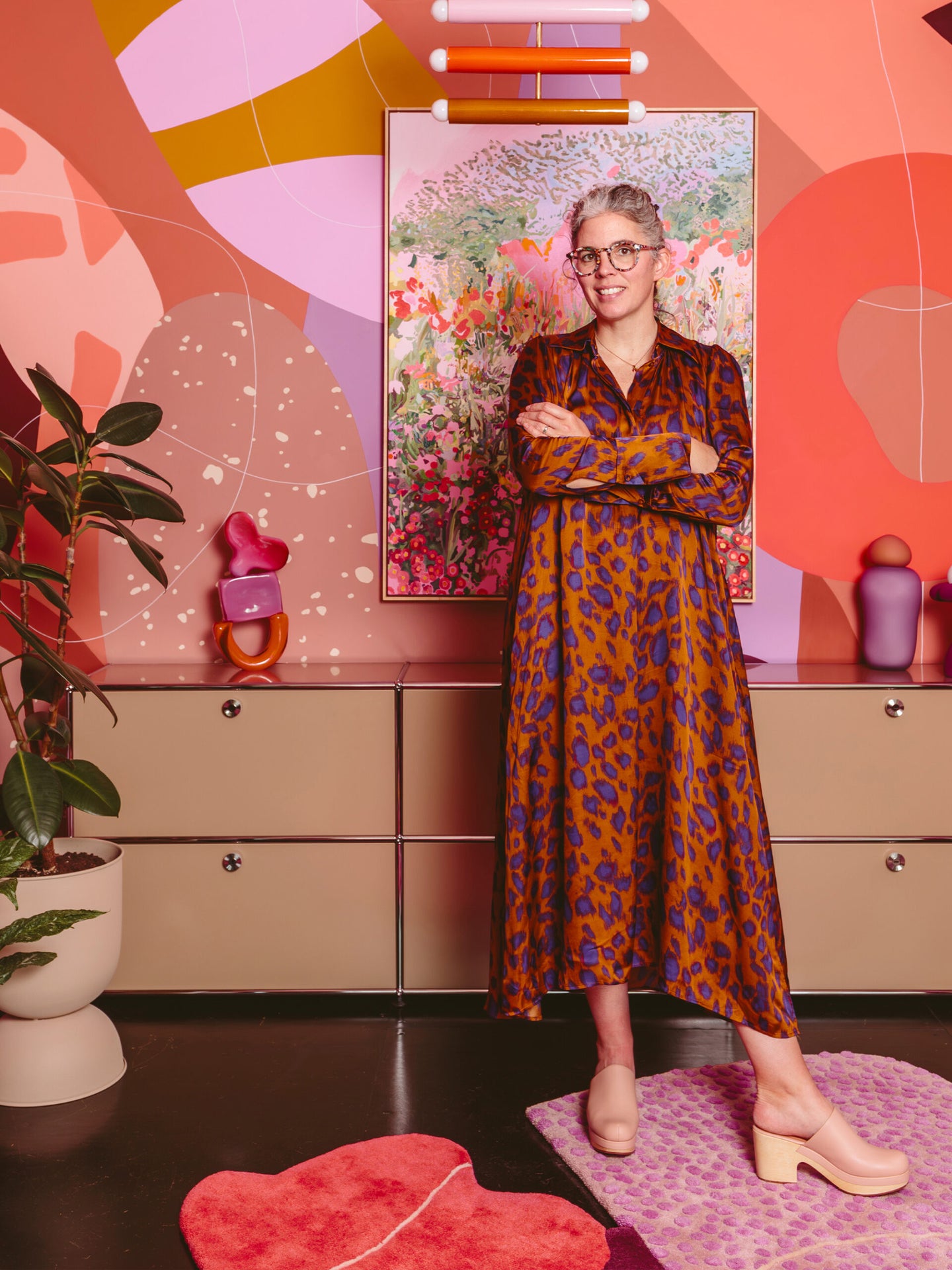 Woman in a leopard dress standing in front of a pink and orange mural