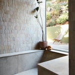 Bathroom with a big window and walk-in tub covered in white tile.