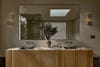 Bathroom with oak wood vanity, big mirror, and low lights. 