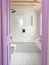 Bathroom with lilac-hued door, white tiles everywhere, and green grout. 