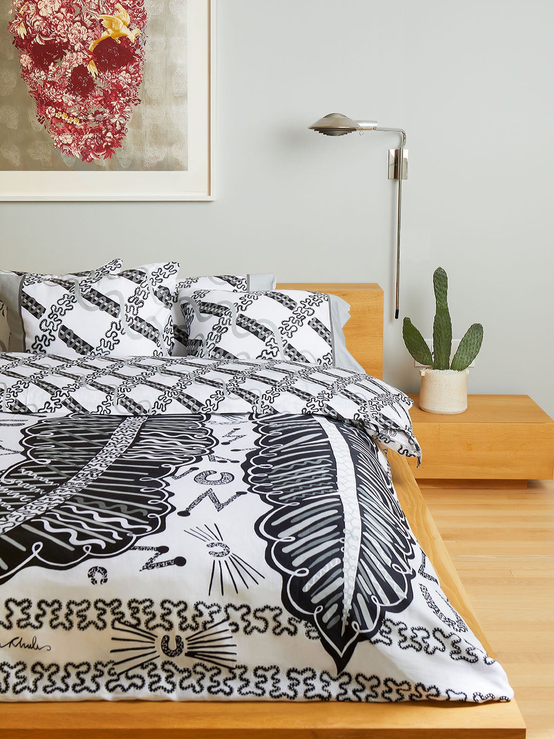 Bed with black and white bedding and a cactus on a nightstand