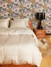 light gray colored sheets in a bedroom with floral wallpaper