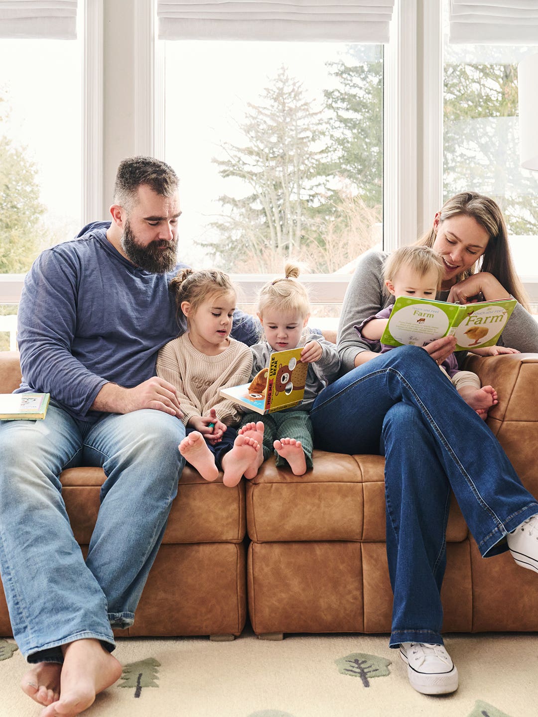 Mom, dad, and three girls on sofa reading books