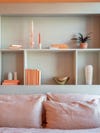 Peach bedding and gray shelving with peach candlestick holders and books