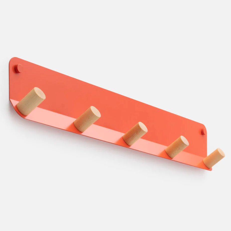 Row of wood hooks on a metal base in a salmon color