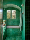 Green bathroom tile in an archway and green walls