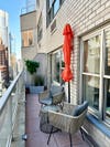 Closed orange half-circle umbrella on narrow New York City terrace