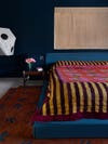 striped bedding on bed in a dark blue room