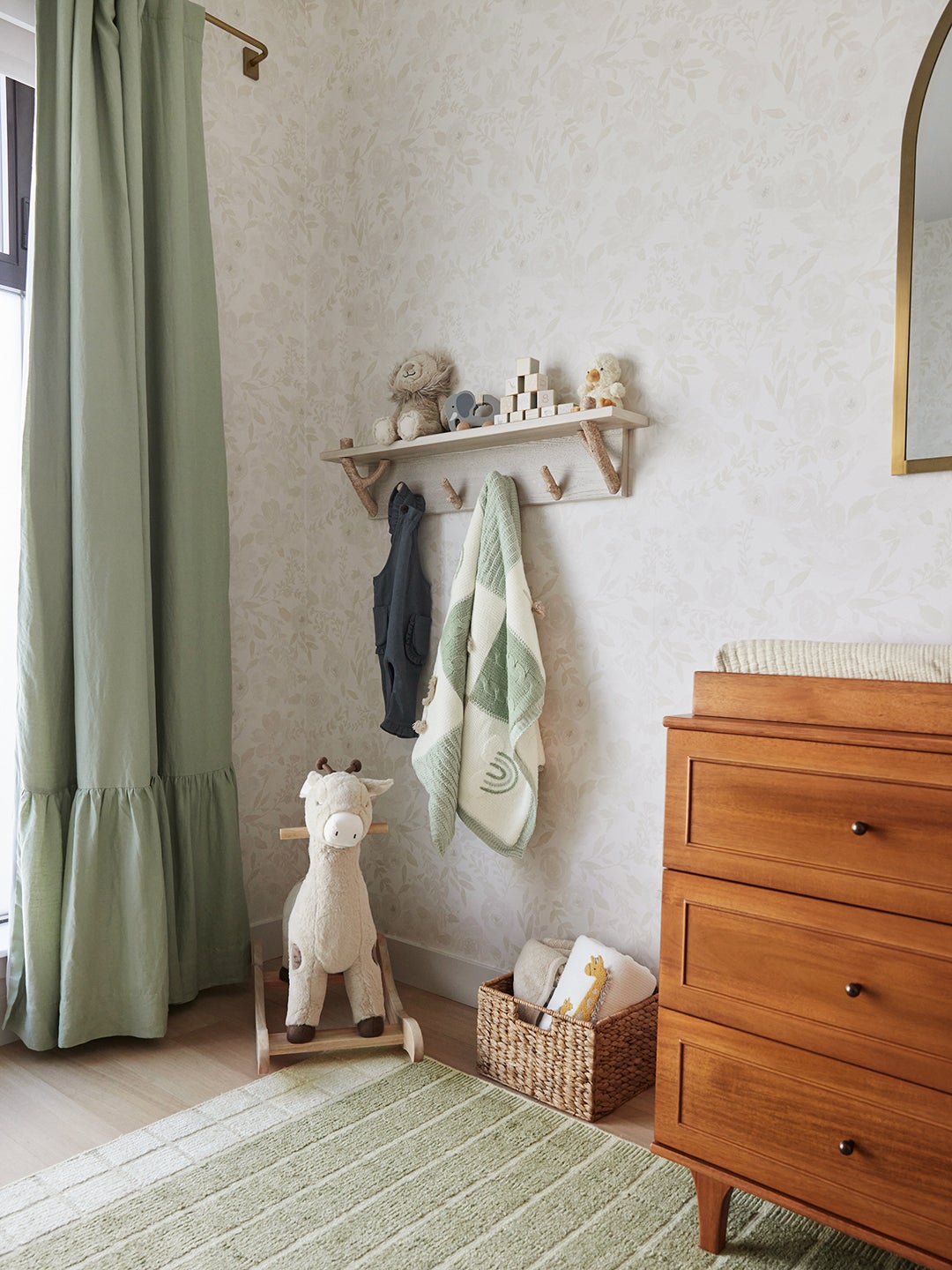 Rocking horse and hooks next to dresser in nursery