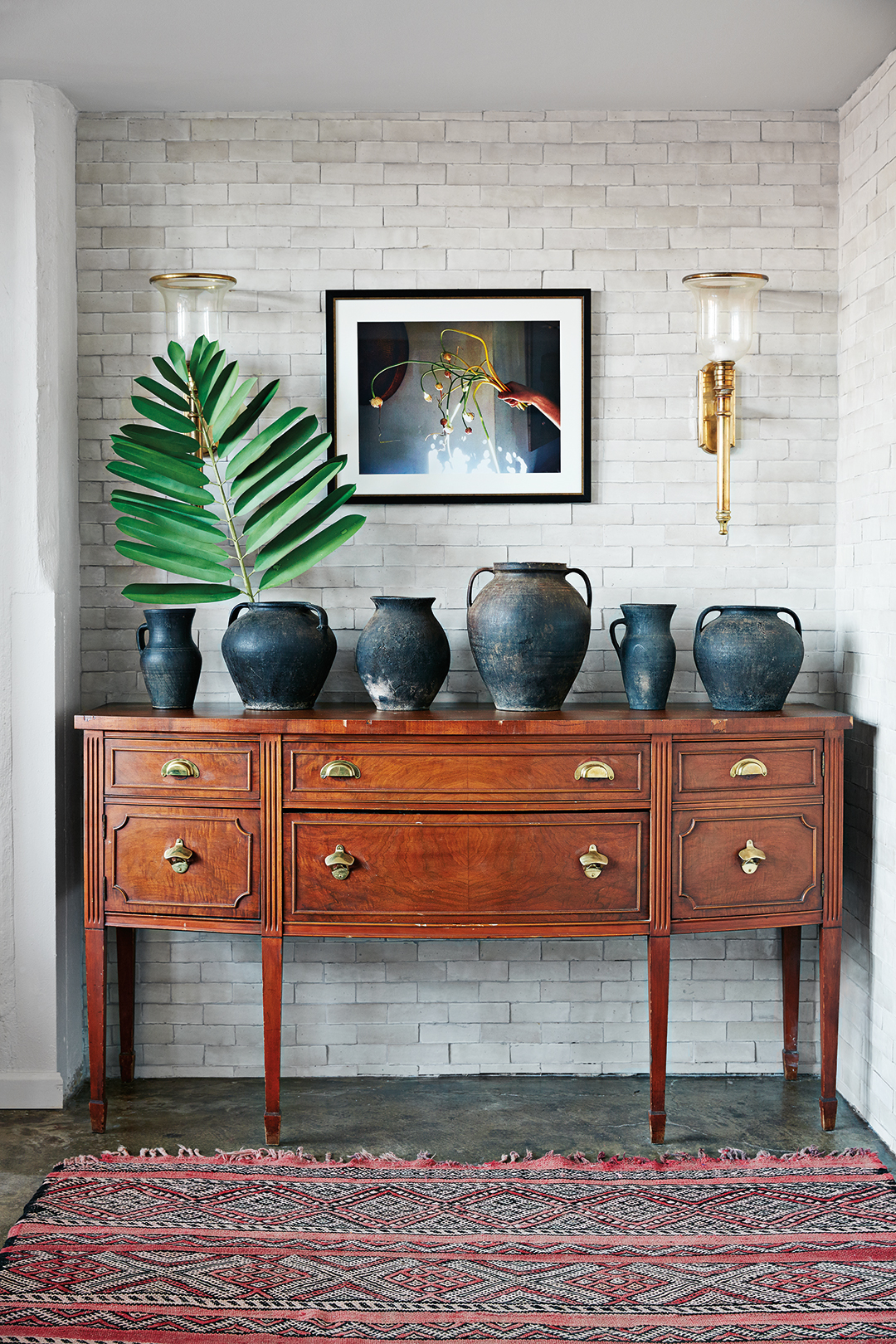wood console with assortment of black vases
