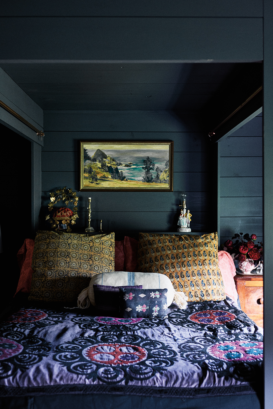 bed layered with textiles in dark green room