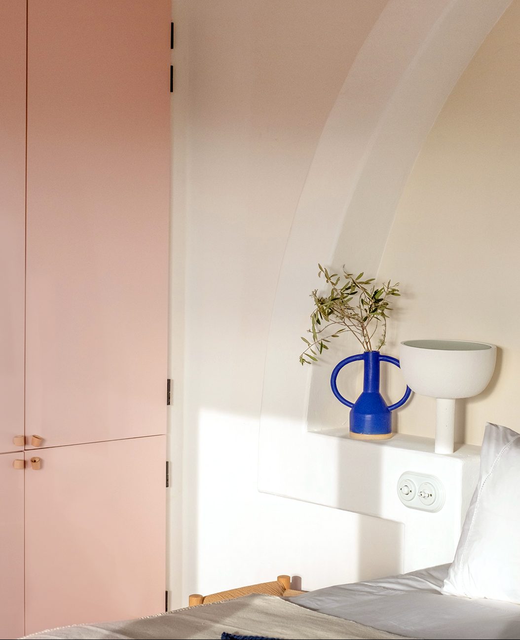 bed with blue-green headboard and pink cabinets