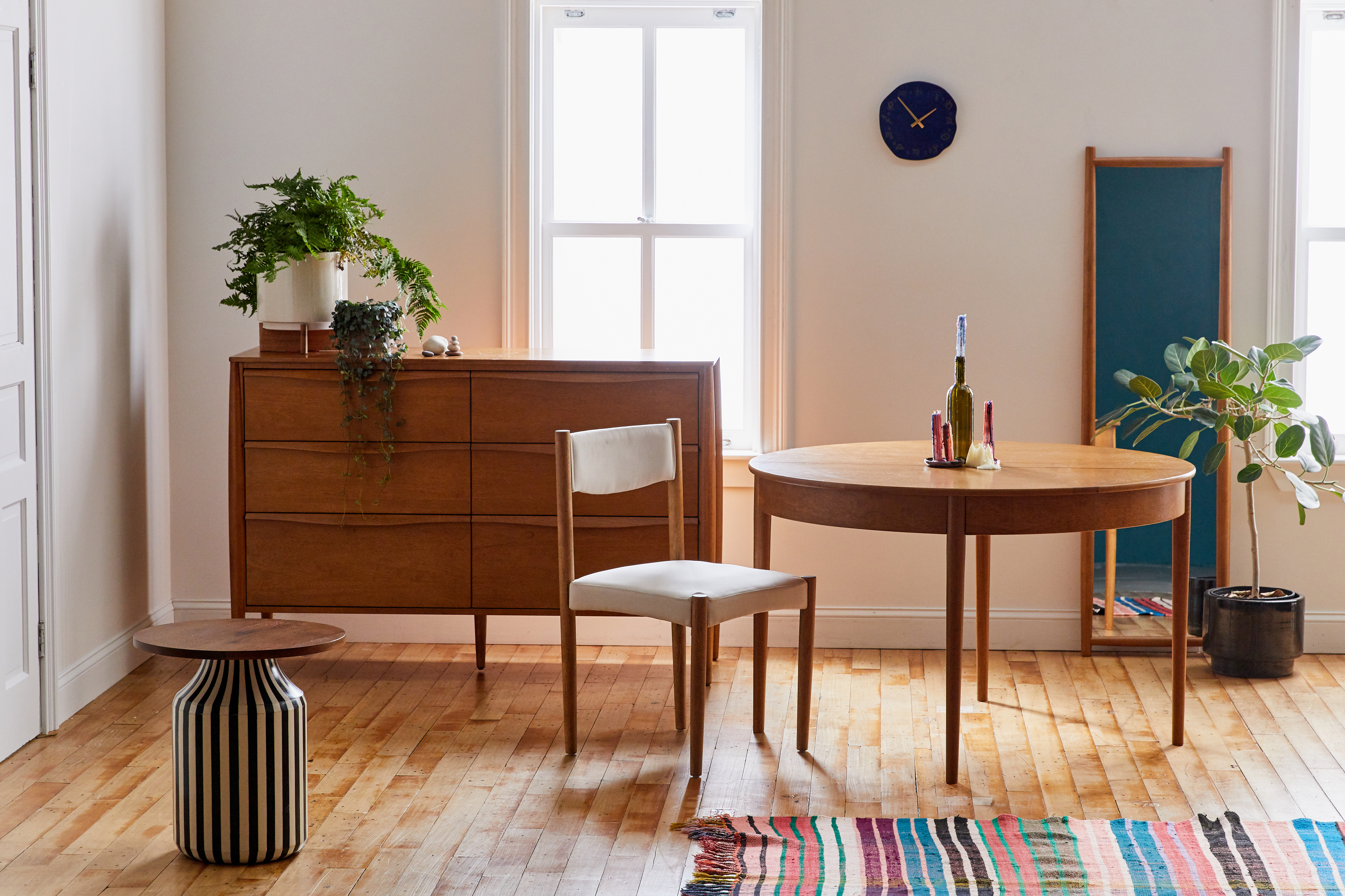Dining room with midcentury style table and chairs, credenza, floor mirror, and colorful striped rug