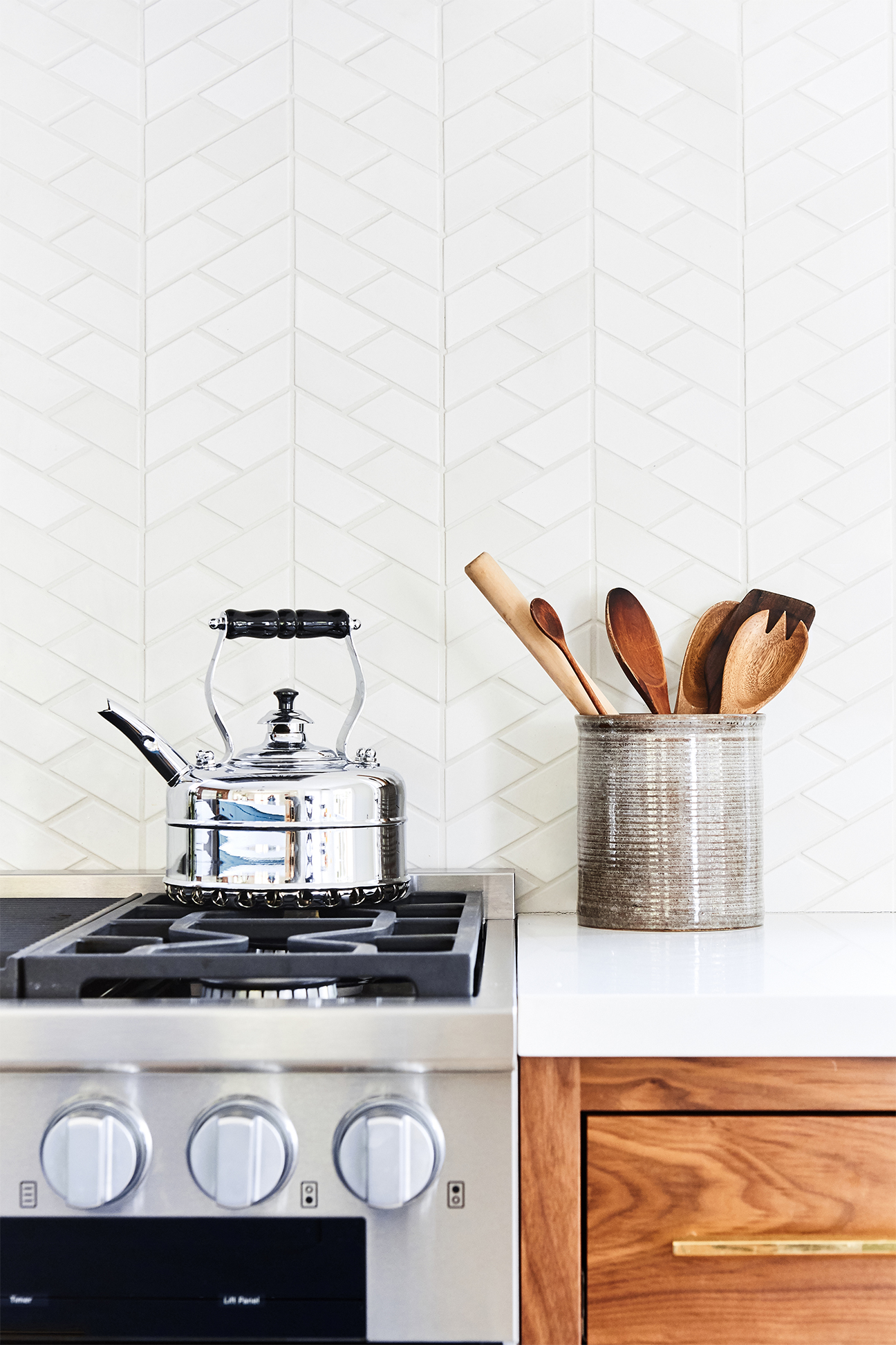 Countertop and stovetop set against white tile backsplasjh