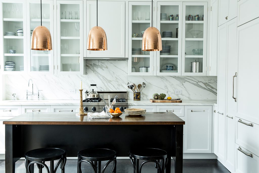 white kitchen with copper pendant lights over black island