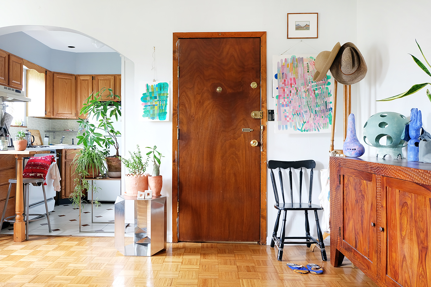 white hallway with wood door and colorful paintings hanging
