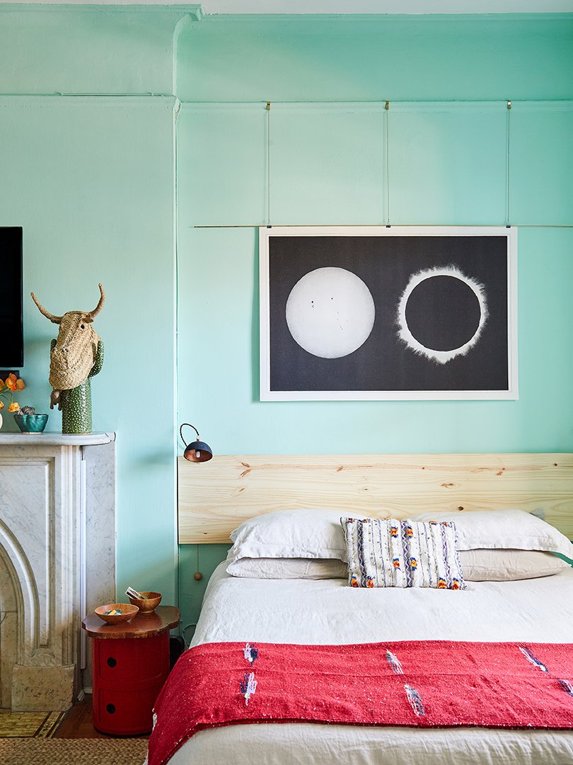 A bedroom styled with stone duvet and red throw at foot with a black-and-white artwork hanging above the headborad.