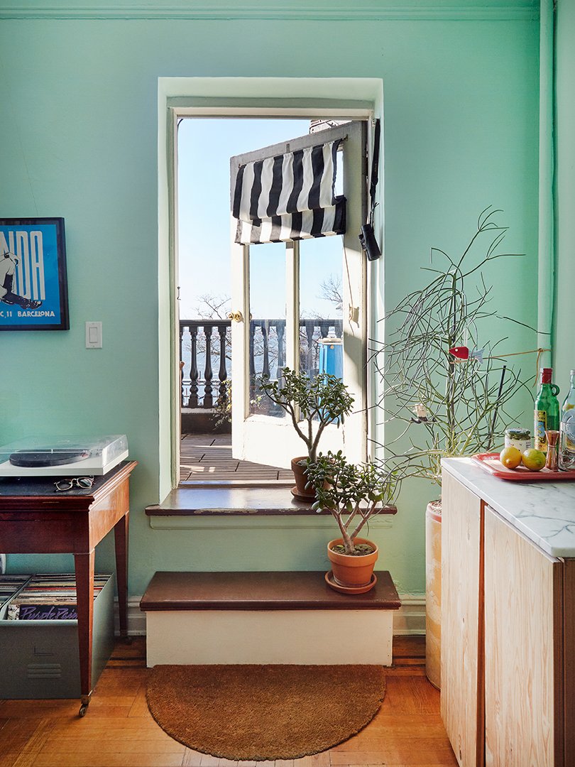 A seafoam wall with a step going up to a doorway that opens onto a terrace