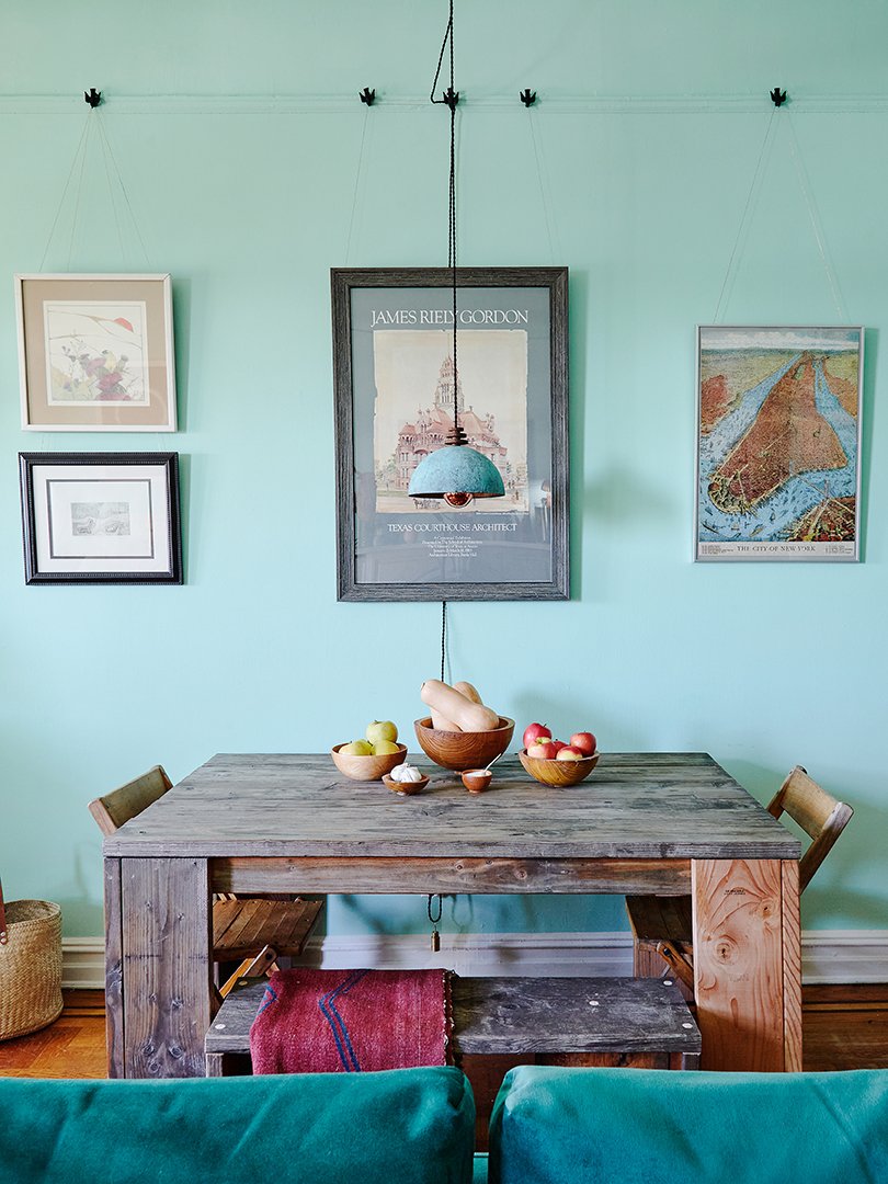 A gallery wall overlooks a wood table and chairs in an open-concept living-dining area