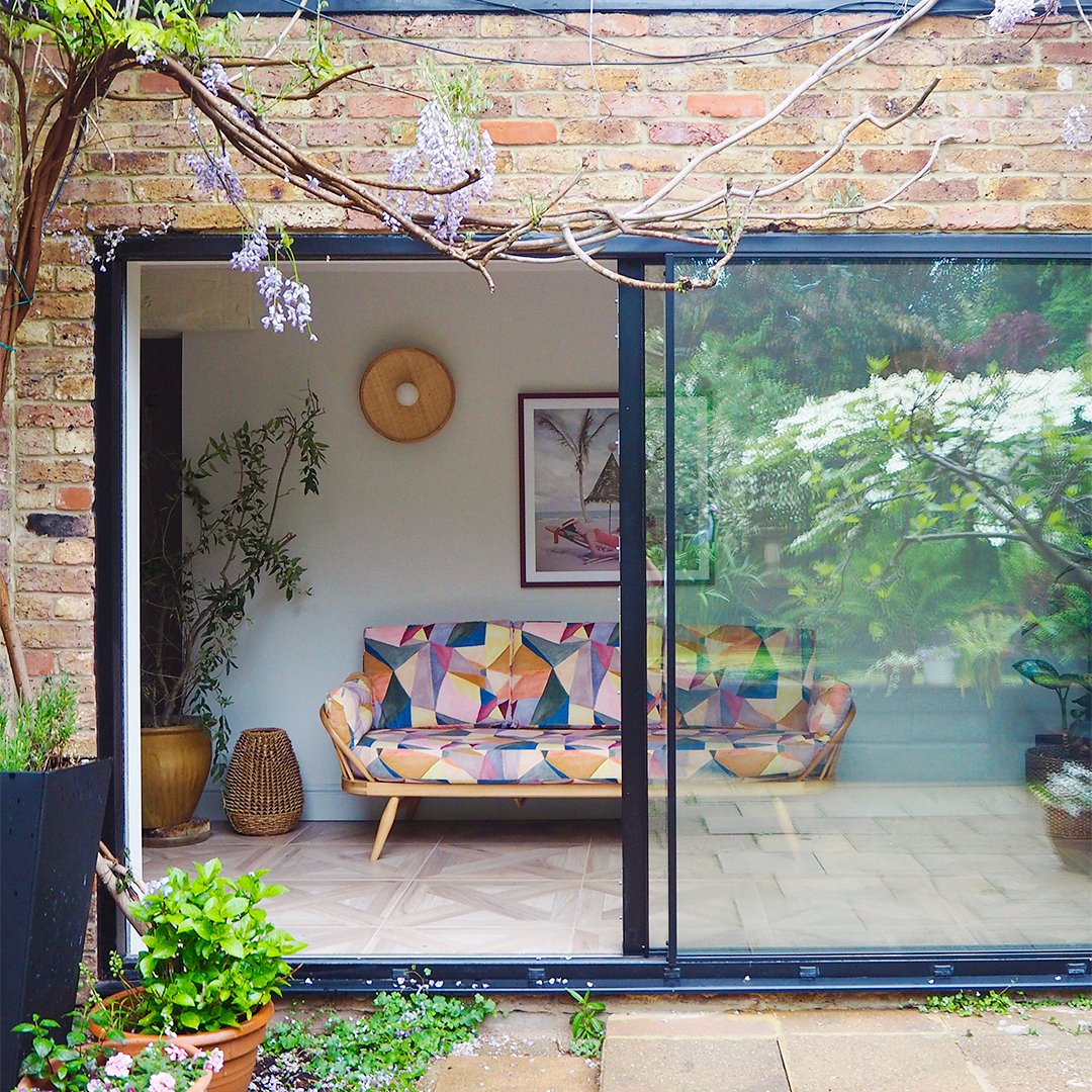 View through sliding glass door into sunroom with colorful sofa.