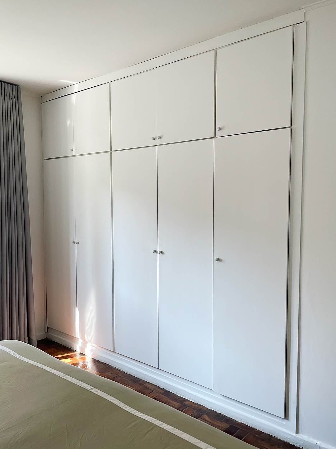 Wall of dated white built-in cupboards