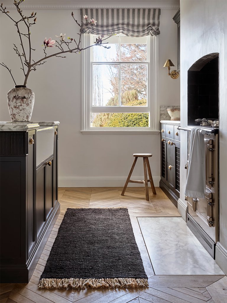 Naturally lit kitchen with black kitchen runner rug.