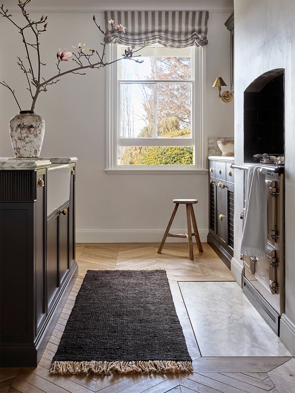 Naturally lit kitchen with black kitchen runner rug.