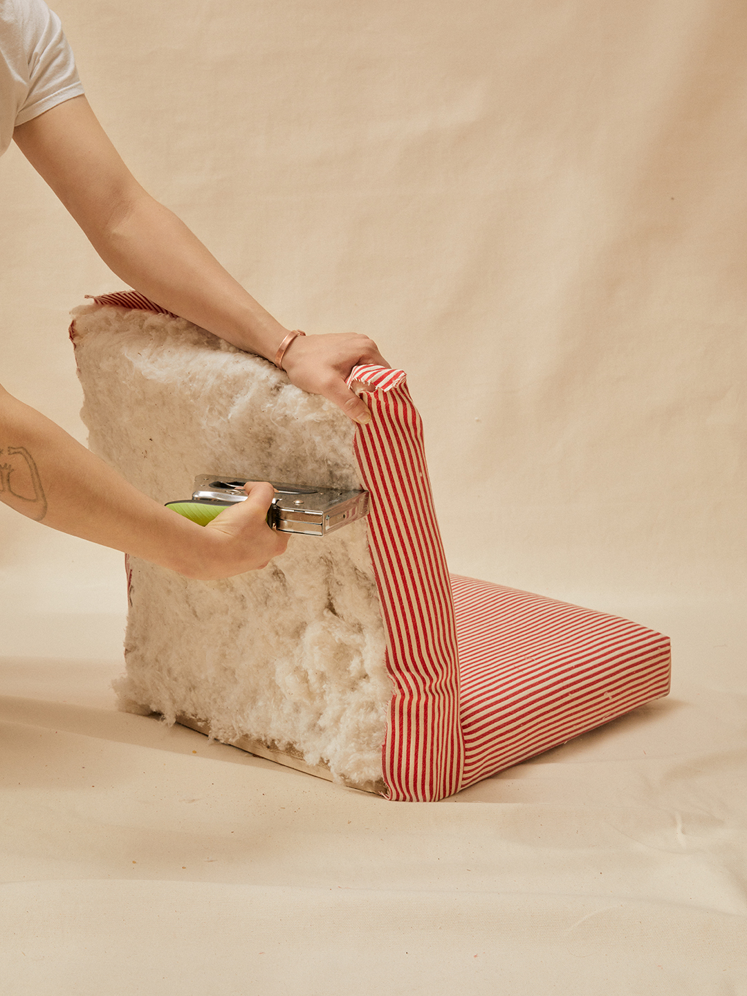 hand stapling red and white striped fabric onto back of chair frame