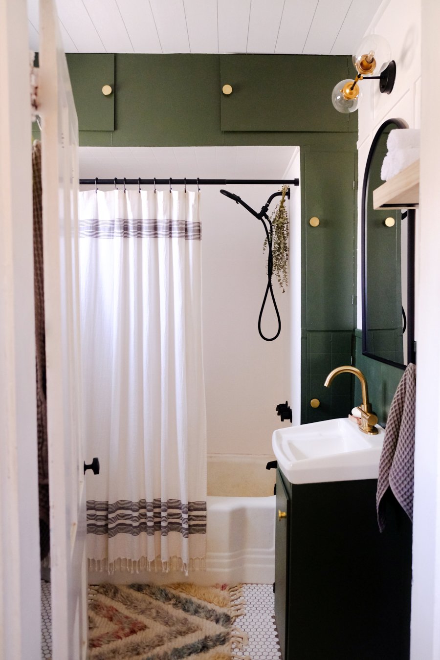 A bathtub surrounded by cabinets painted in a moody green