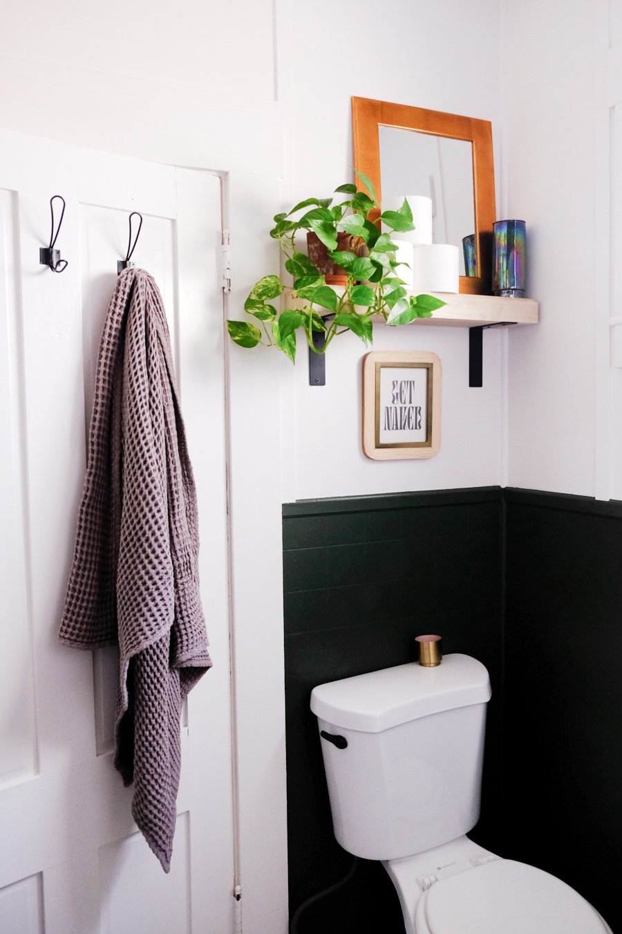 A toilet in the corner of a bathroom with moody green paint below chair rail