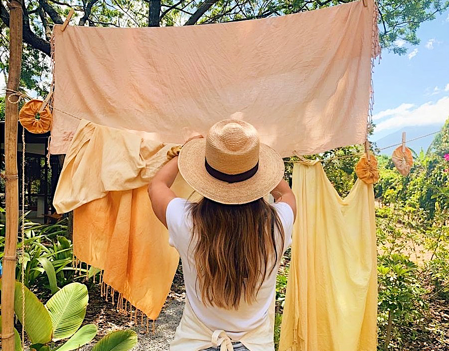woman hanging naturally-dyed sheets on line