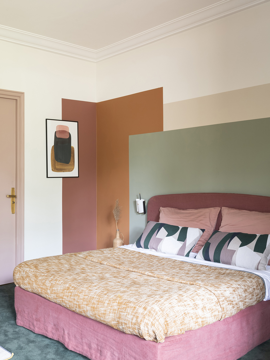 Bedroom with colorblocked wall in terracotta, sage, and beige.