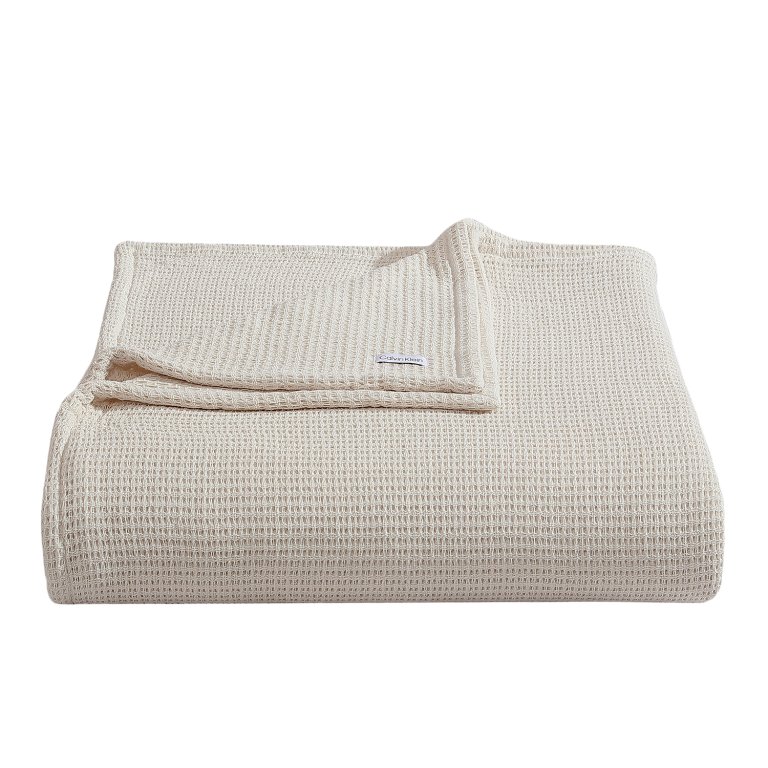  Product shot of cream-colored woven blanket.
