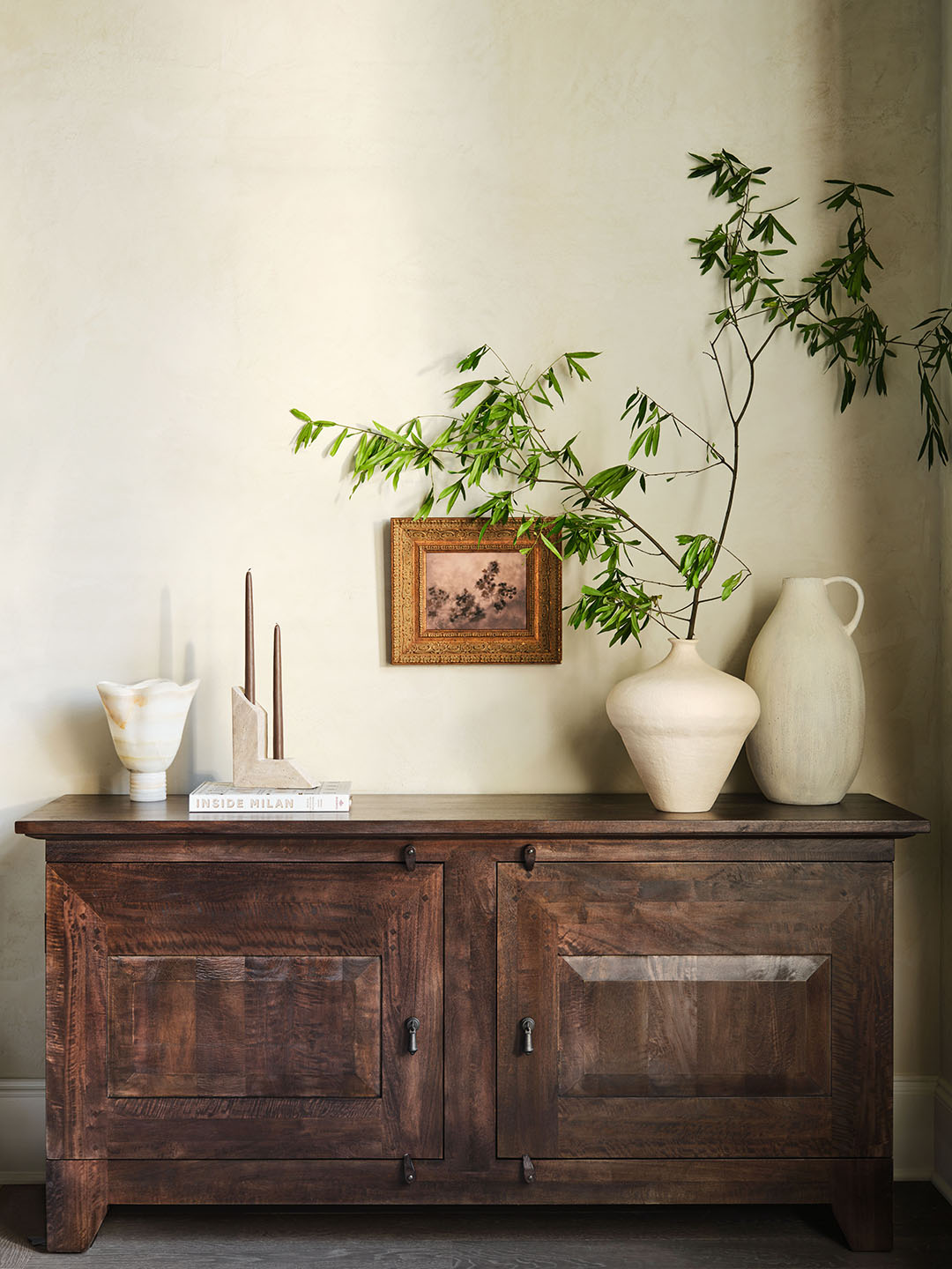 Wooden storage cabinet topped with white ceramic vases