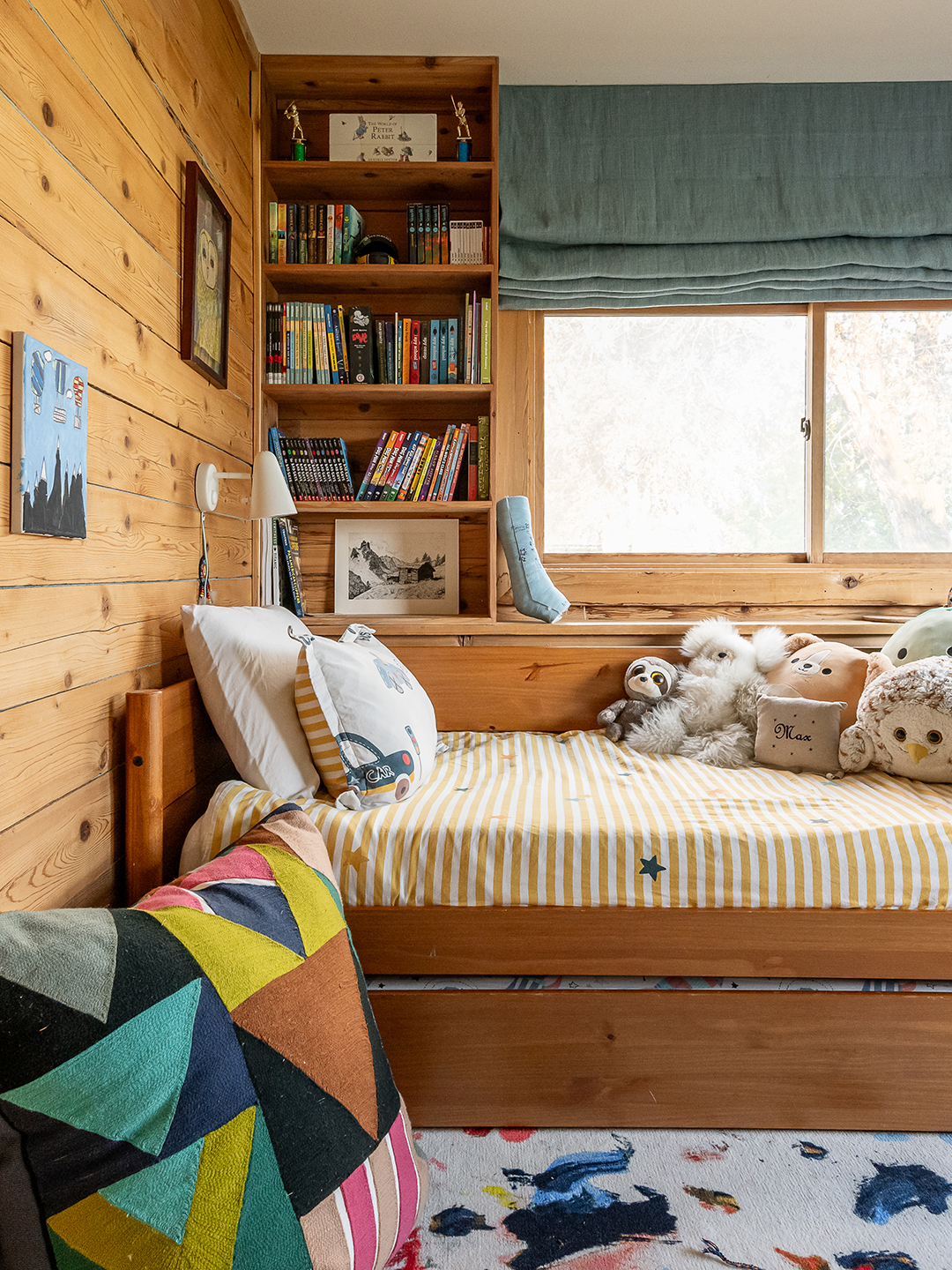 A child's bed with built in shelving behind it