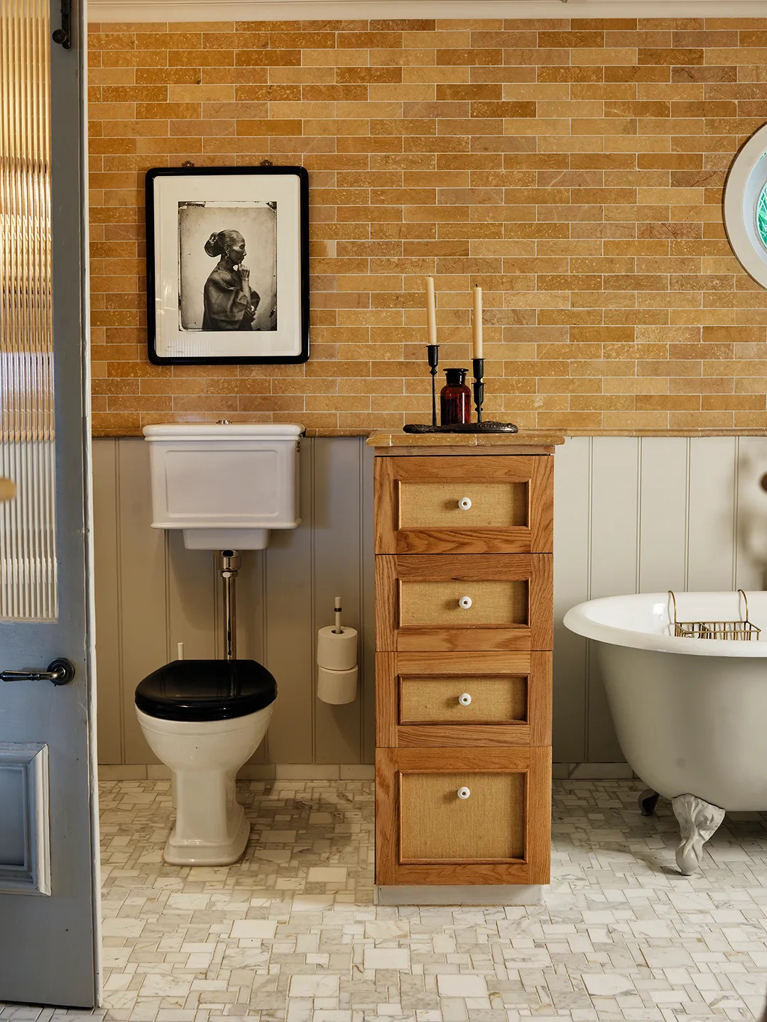 Grey cast-iron tub in a bathroom with marble mosaic tile