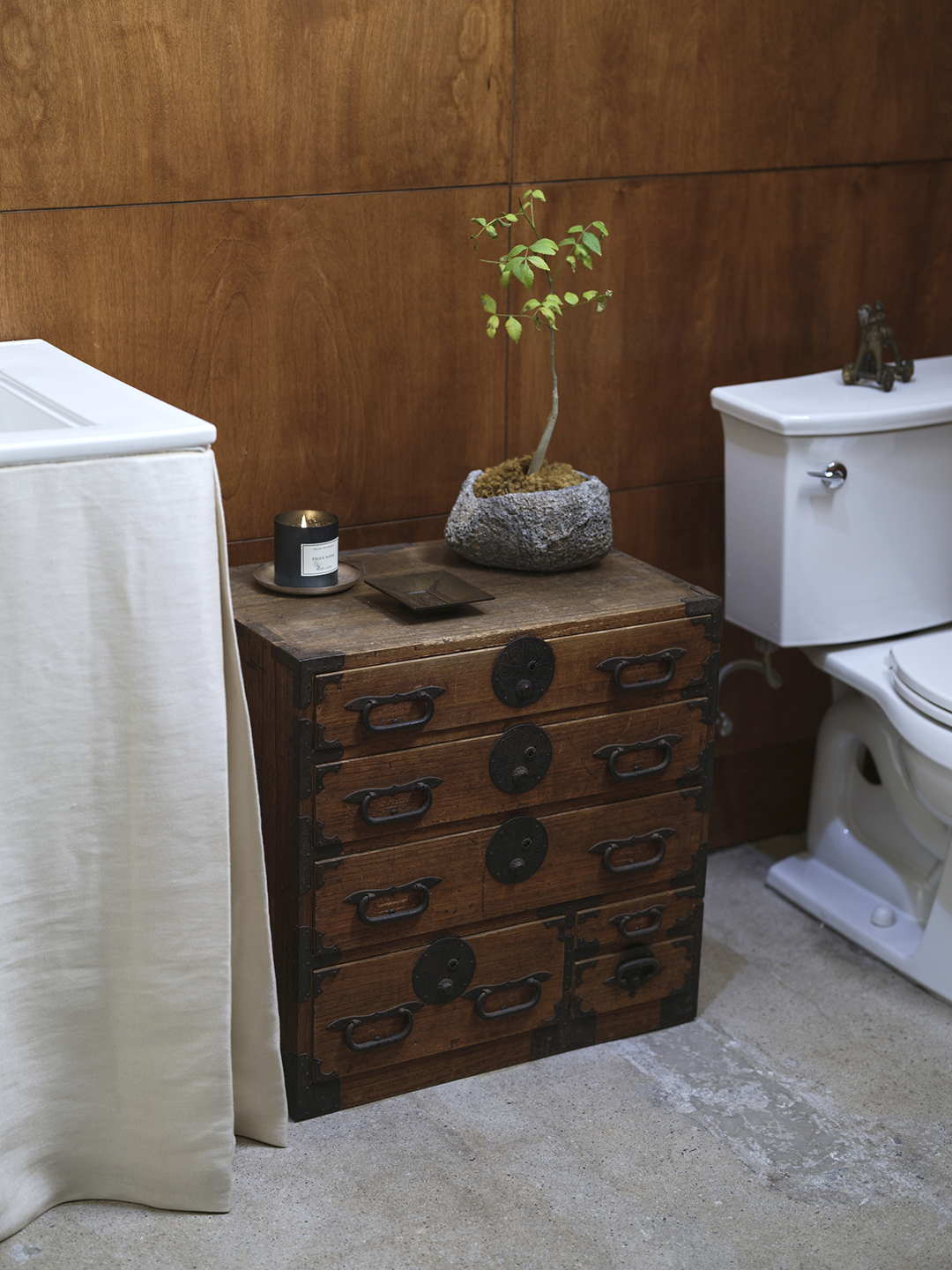 A chest of drawers between the sink and toilet 