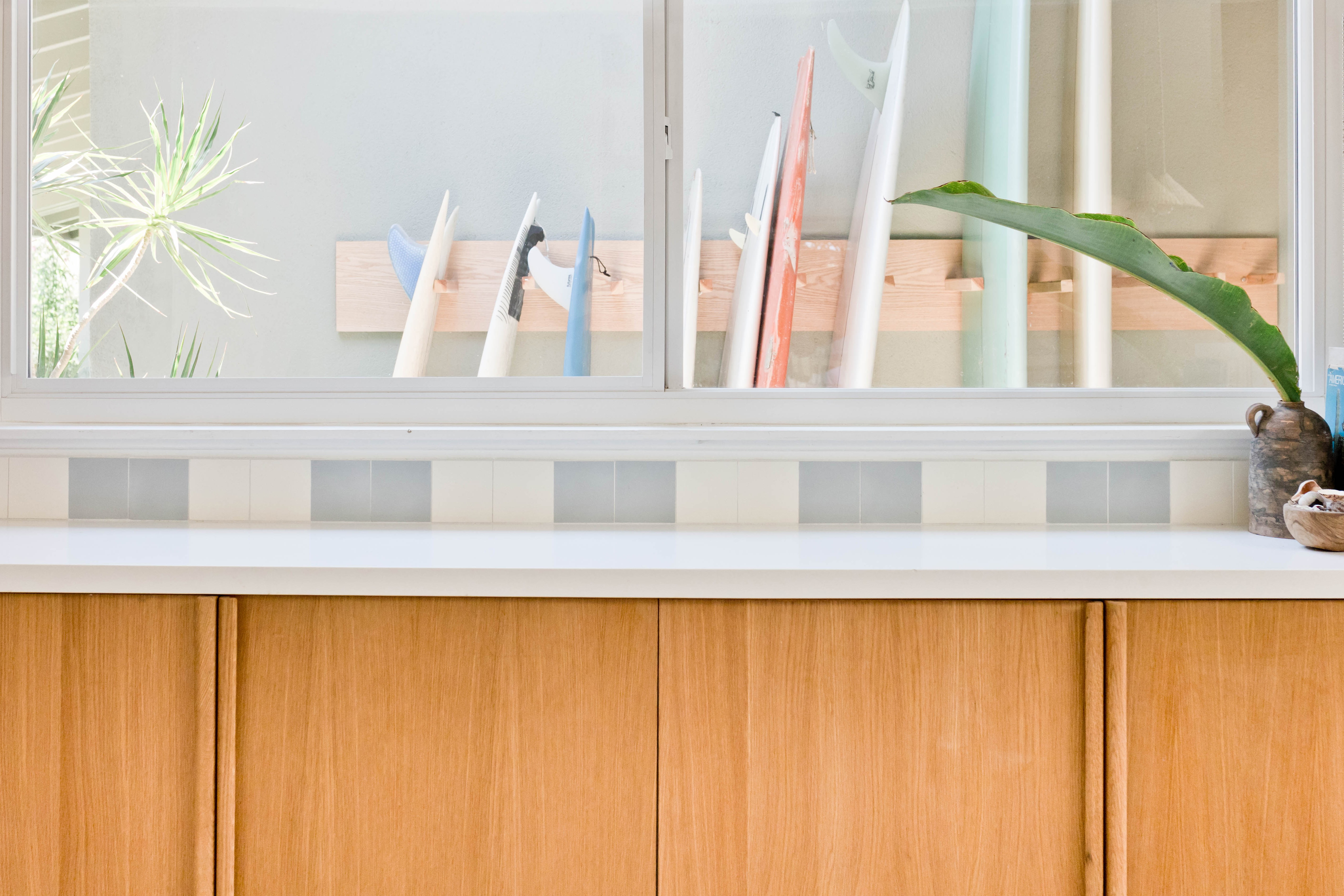 Picture window in kitchen showing surfboard rack outside.