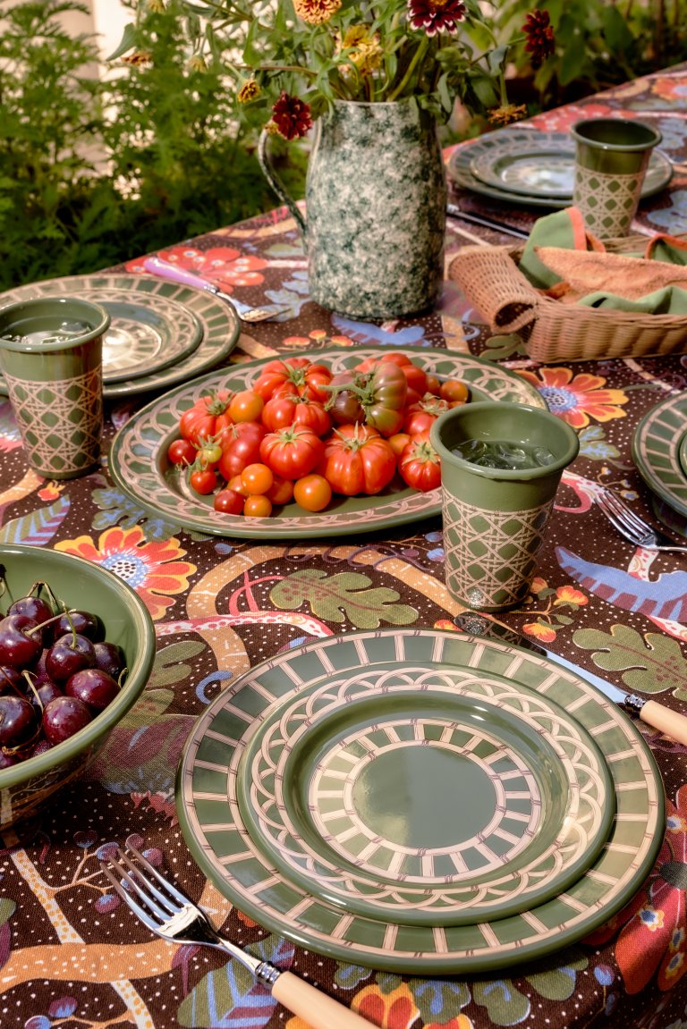 Table set with green enamelware dinnerware with tomatoes on a plate.