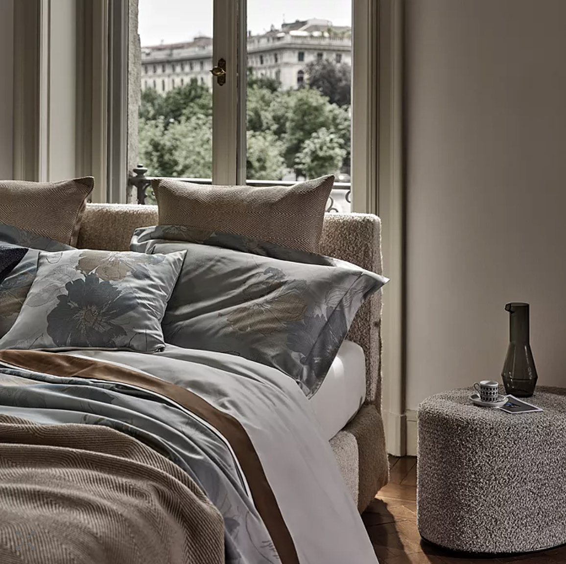 Bed against European-style window with rumpled floral sheets. 