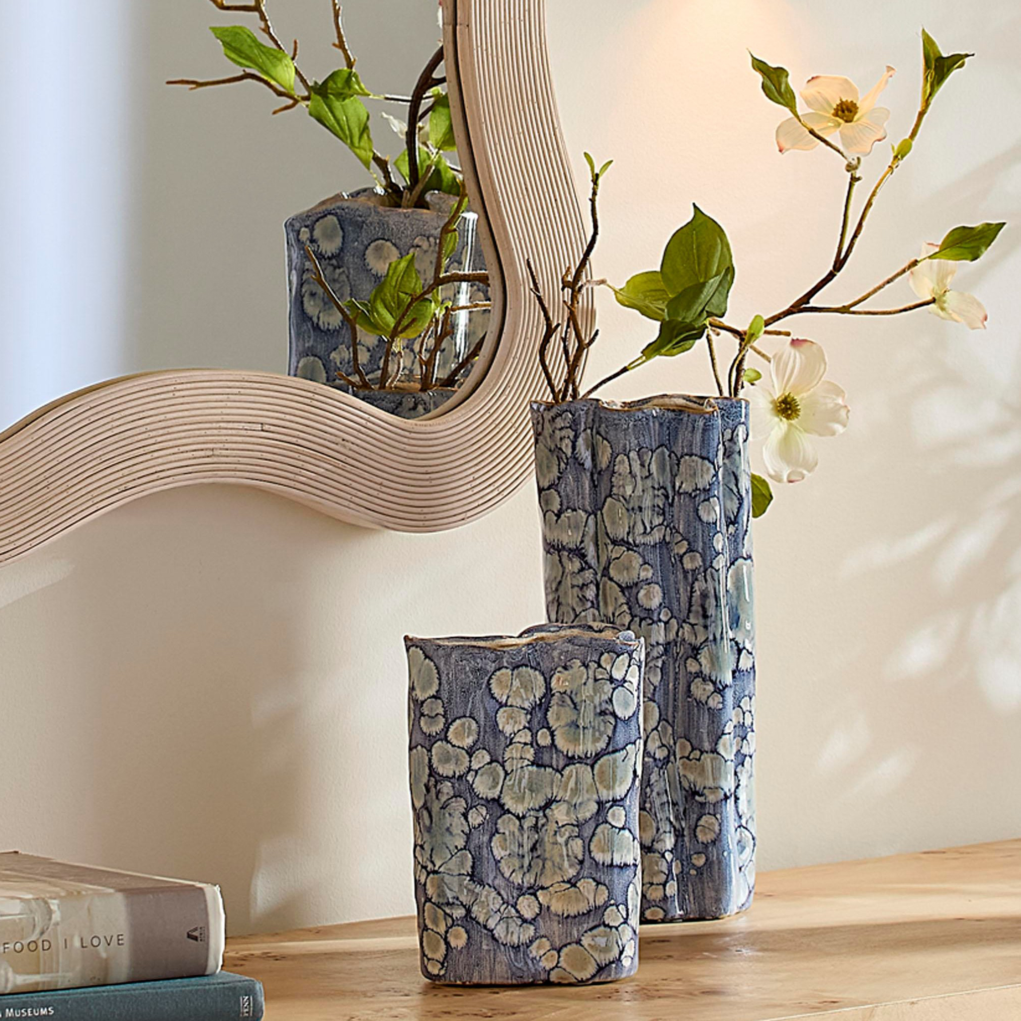 Two blue vases with branches on a hallway console with mirror in top left corner.