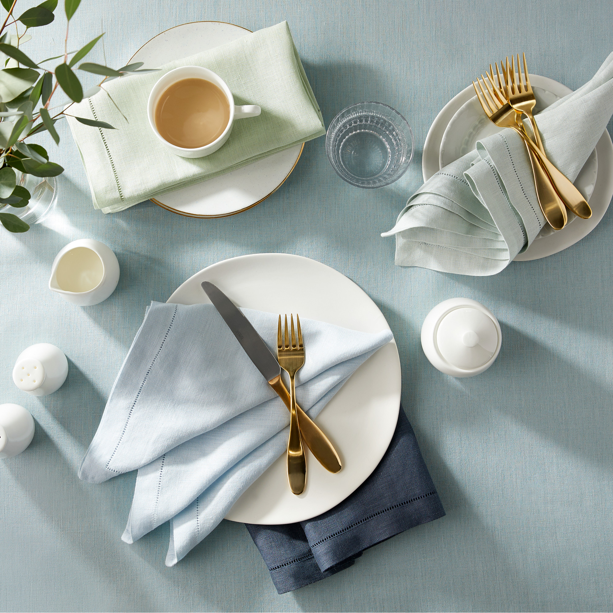 Overview of table set with sky blue linens and breakfast food. 