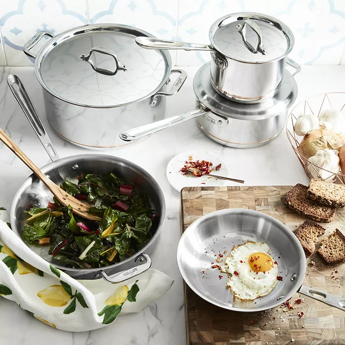 Stainless steel cookware showing breakfast being made with fried egg and greens. 