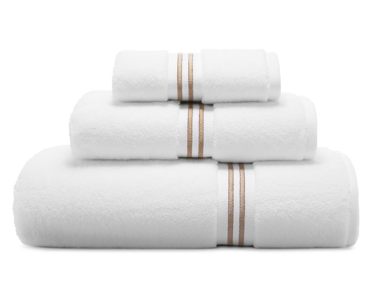  Stack of three white towels with contrast gold stitch borders.