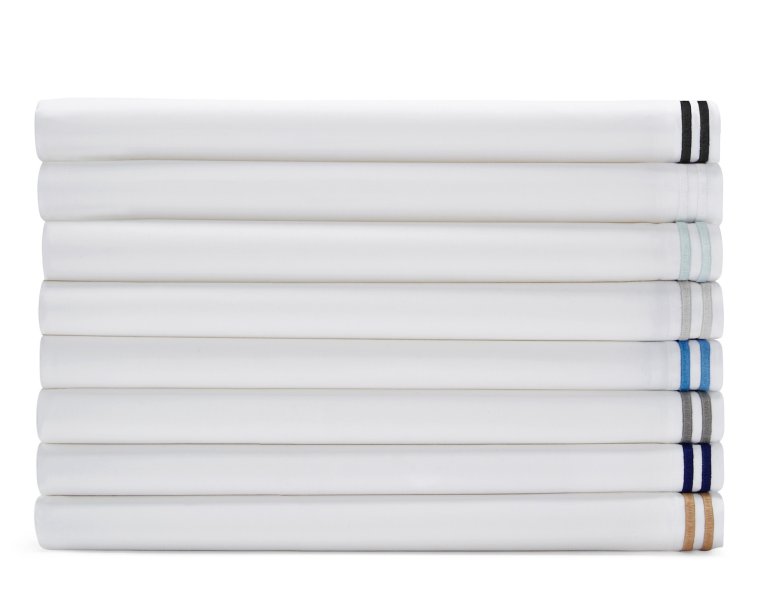  Stack of white sheets with different colored satin stripe stitching on edge.