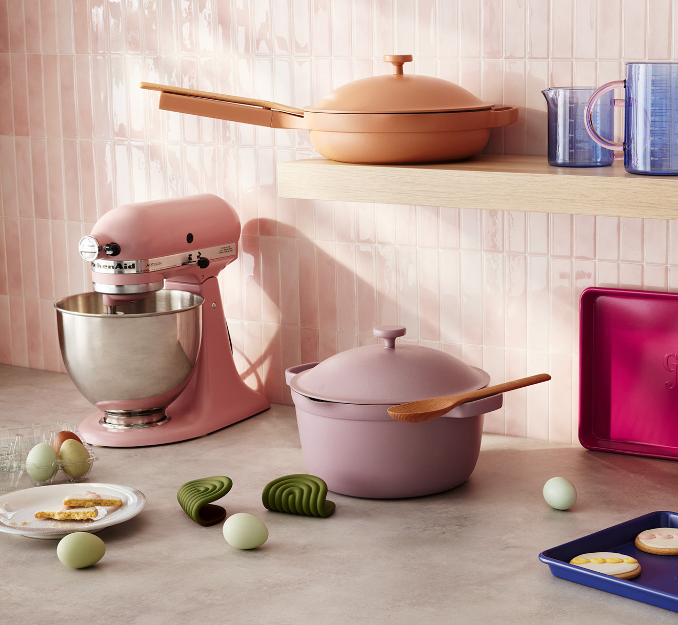 Pink and purple cookware in beige kitchen background.