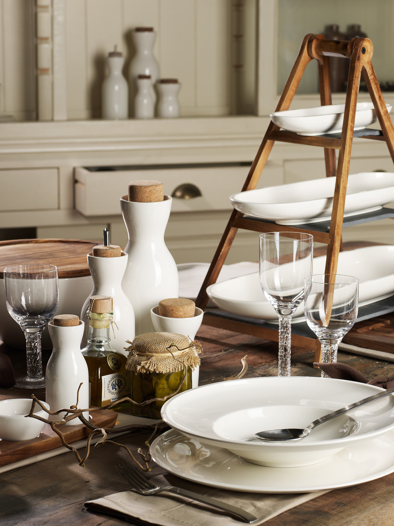 Breakfast table set with white dishes and tiered wood tray.