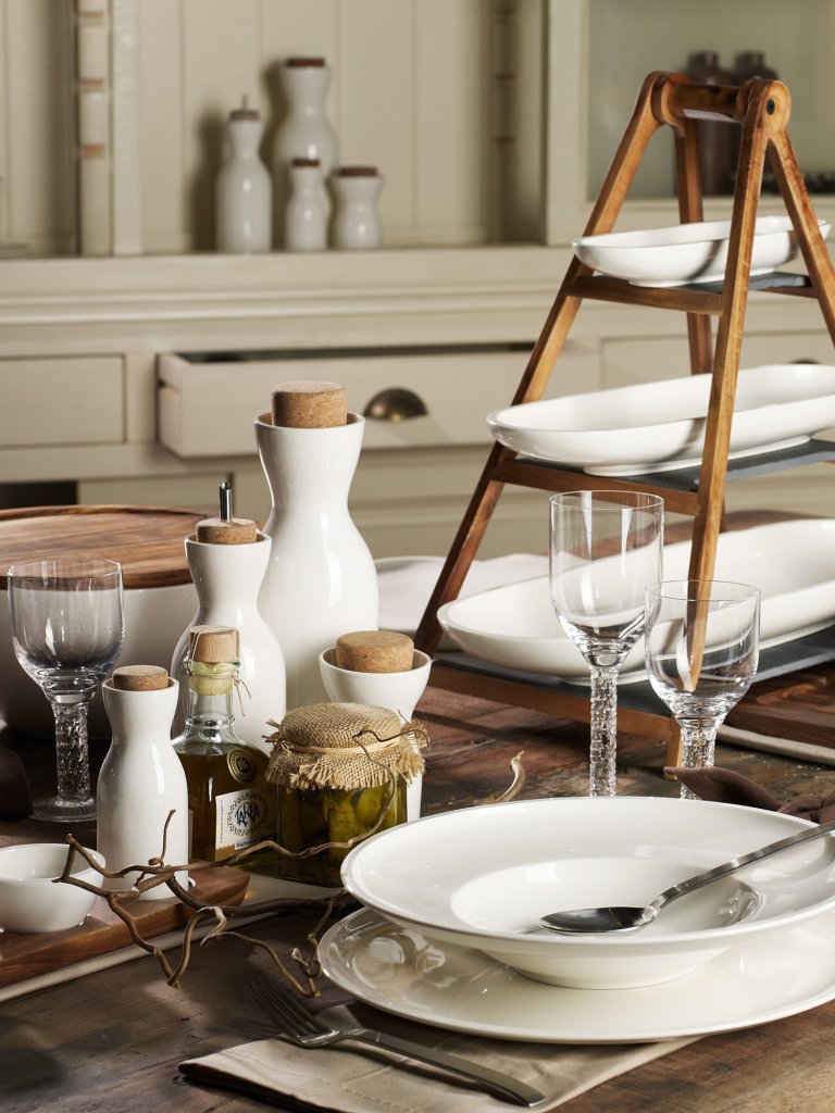 Breakfast table set with white dishes and tiered wood tray.
