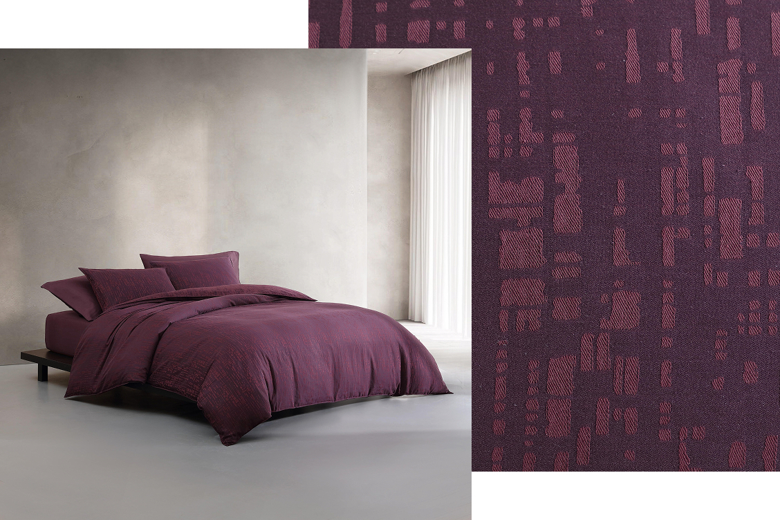 Bed near window made with maroon colored sheets and sheet fabric swatch layered behind image.